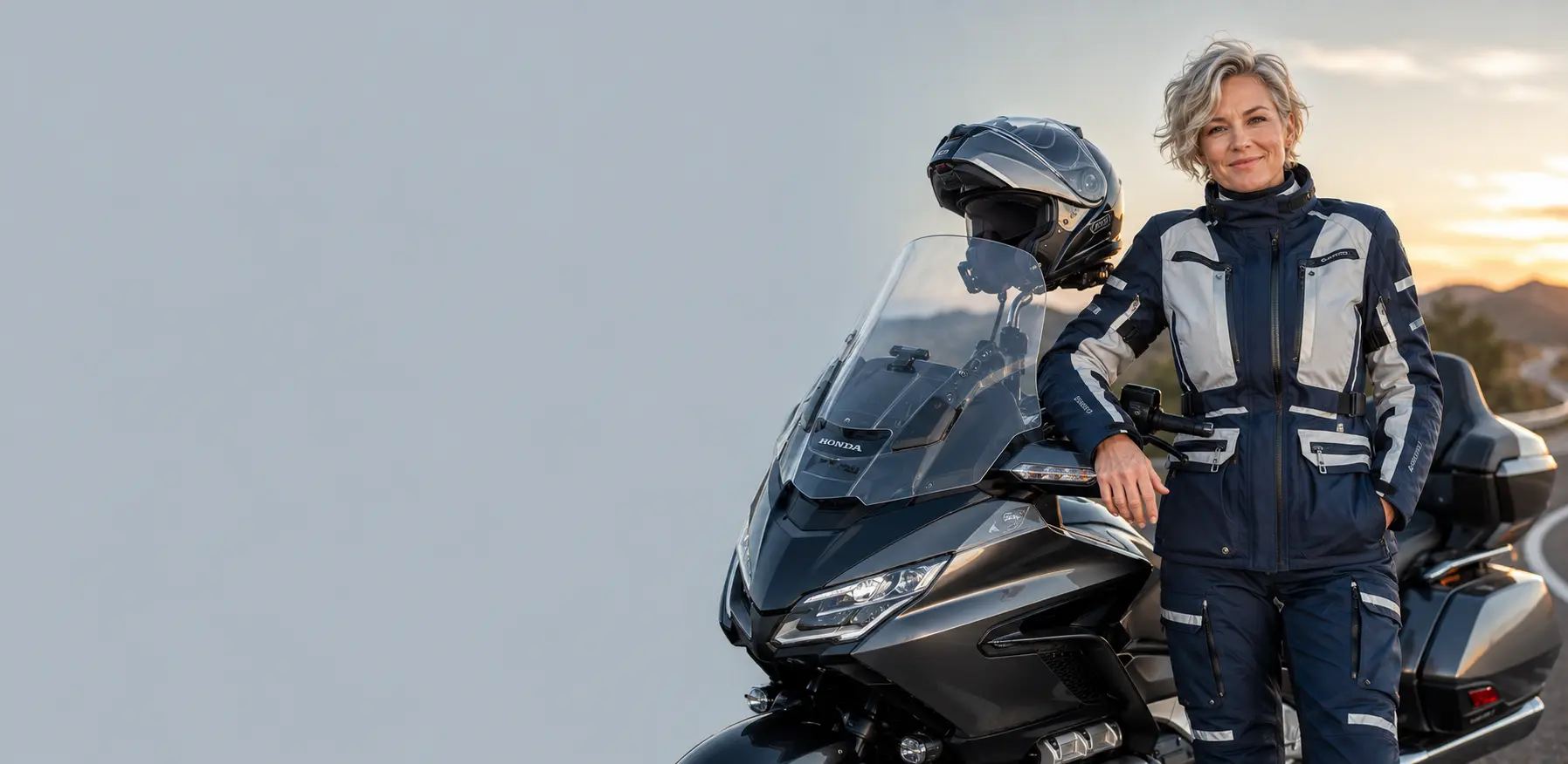 Comfortabel tour motorpak voor dames met een tourmotorfiets en een systeemhelm tijdens een rit bij zonsondergang.